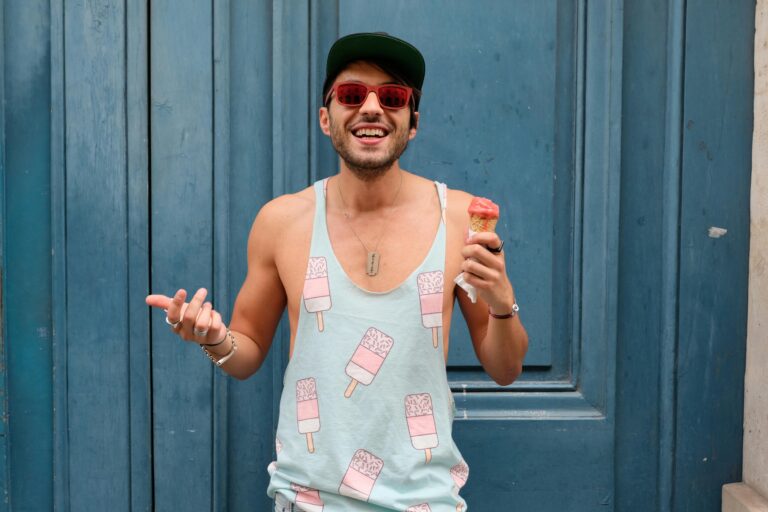 Happy man in Paris enjoying ice cream against a blue door. Fashionable and fun summer vibe.